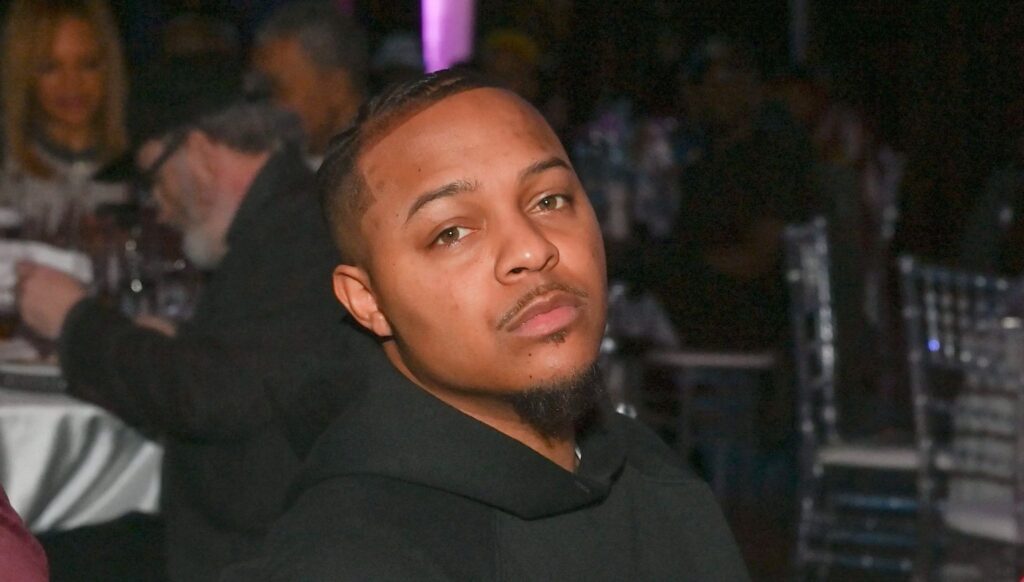 A close-up photo of Bow Wow attending an event, dressed in a black outfit with a confident expression