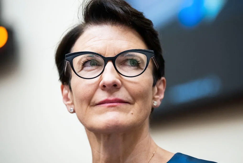 A professional woman wearing stylish black glasses, looking confidently upward during a corporate event — concept image for Jane Fraser business leadership.