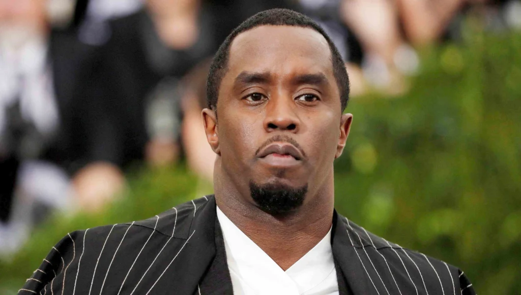 A close-up photo of an unidentified man in a formal pinstripe outfit at an event, used for an article discussing p diddy net worth.