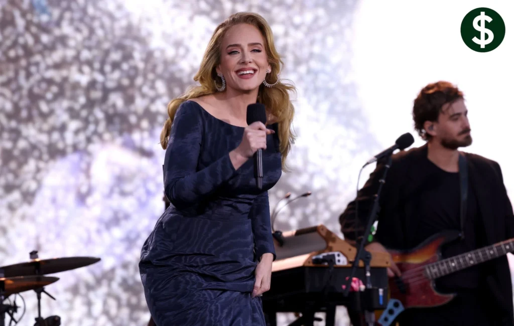 Adele performing live on stage holding a microphone during a concert, highlighting her successful music career and Adele Net Worth.