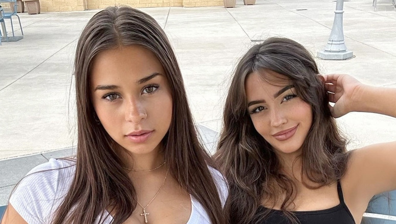 Two women sitting outdoors, posing for the camera with relaxed expressions; image used in an article discussing Sophie Rain Net Worth and her OnlyFans career.